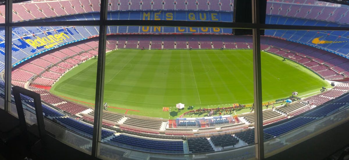 Wide view of Camp Nou stadium showcasing its vast seating and green pitch.