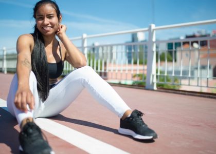 Woman in athletic wear relaxing outdoors on a sunny day, showcasing fitness style and confidence.